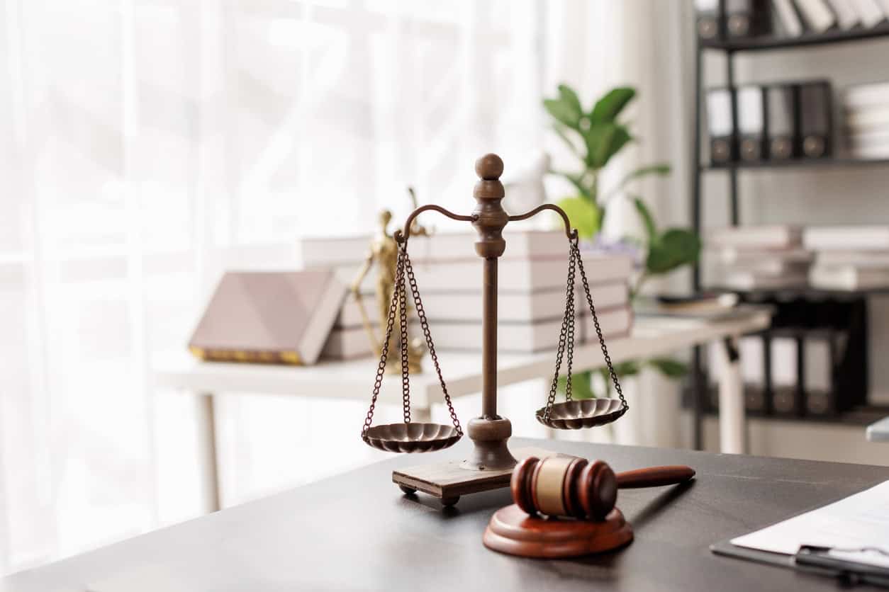 Scales of justice and a judge's gavel on a desk in a small law firm office.