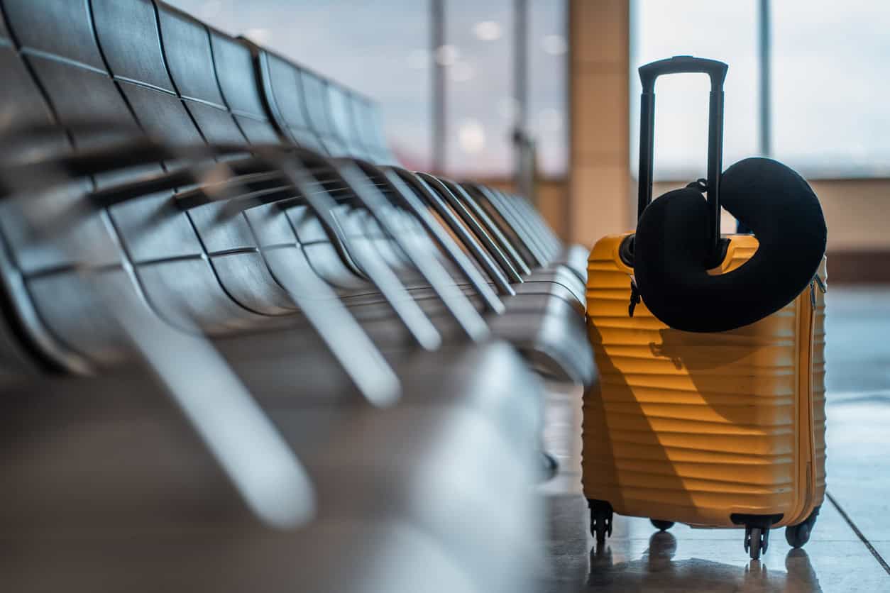 Suitcase and travel pillow in an airport terminal.