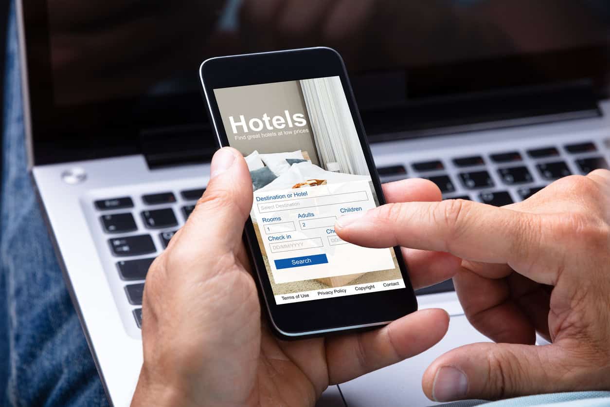 Person using a smartphone to search for and book a hotel room online.