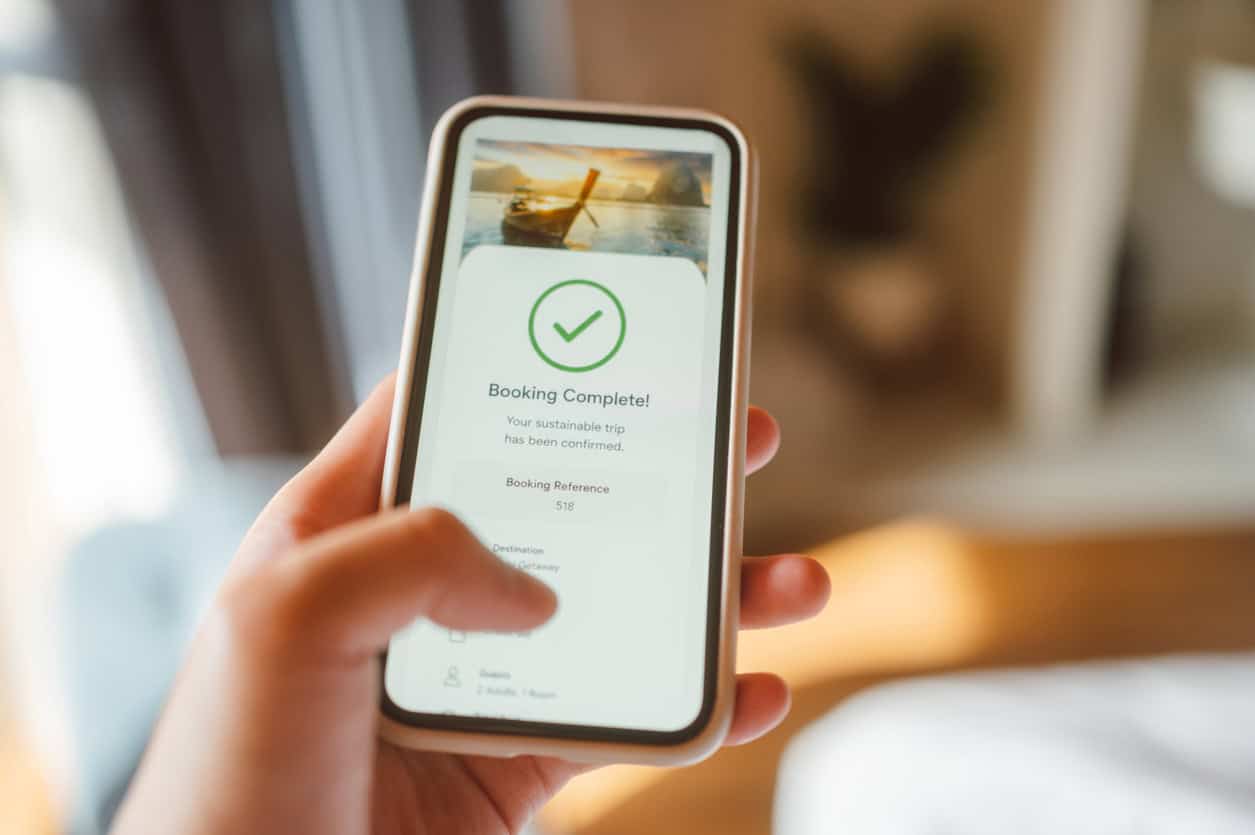 Smartphone displaying a “Booking Complete!” confirmation screen for a travel reservation.