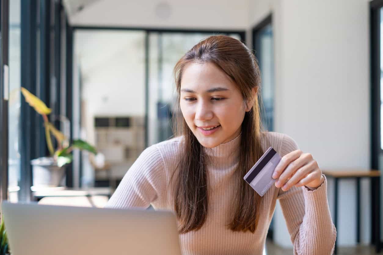 Woman holding a credit card while using a laptop to manage business finances.
