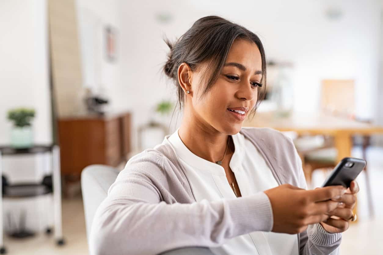 Woman smiling while reading credit card news on her smartphone about major changes coming in 2027.