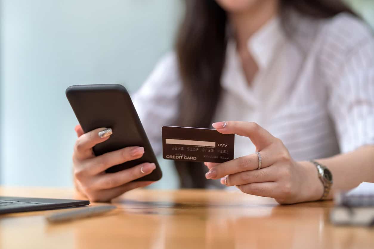 Woman holding a credit card and smartphone while making an online payment.