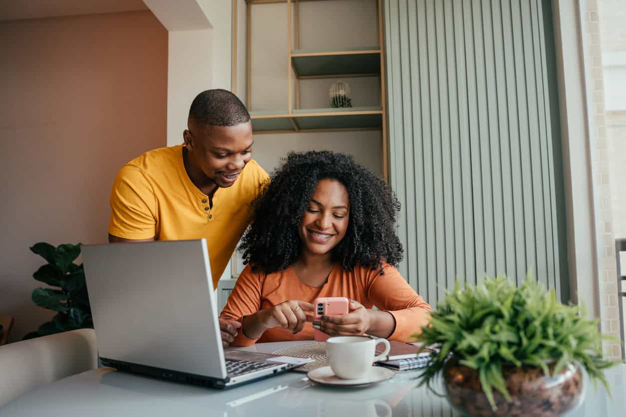 Couple reviewing financial information on a laptop and smartphone at home.